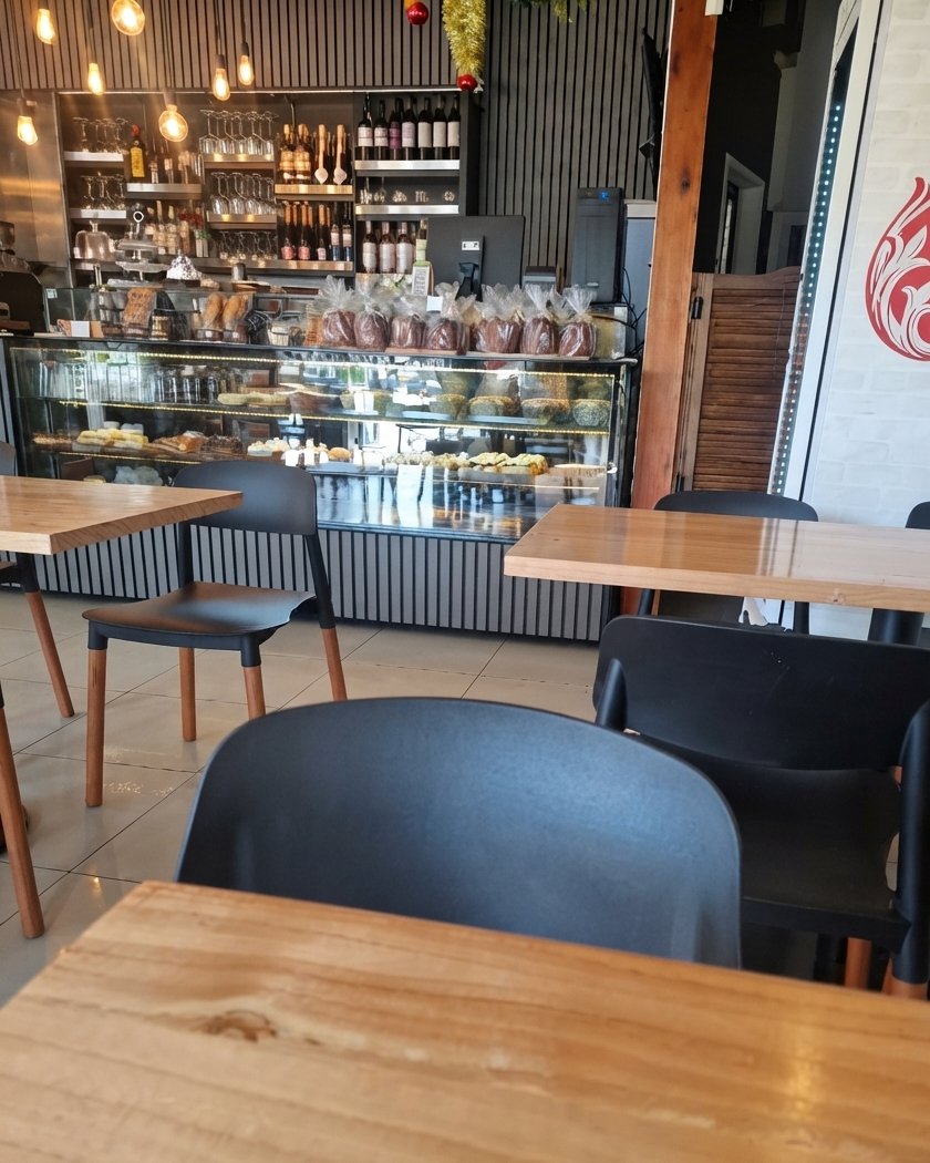 El salón con mesas de madera y, al fondo, la vitrina y los estantes de vinos
